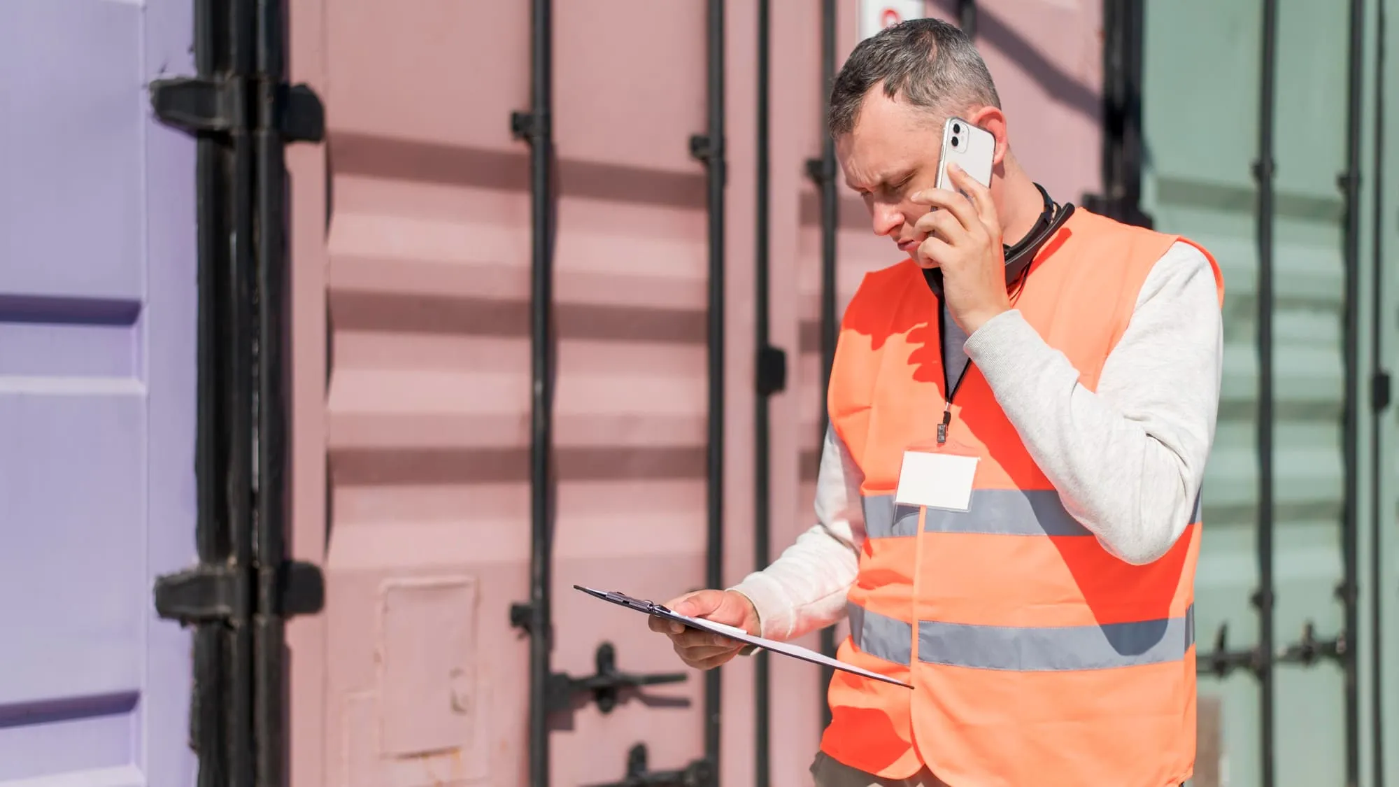 Técnico de logística atendiendo una incidencia por teléfono junto a un contenedor